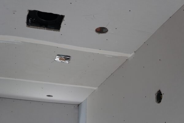 Bathroom recessed lighting and fan light installation during drywall rough-in phase before finishing.