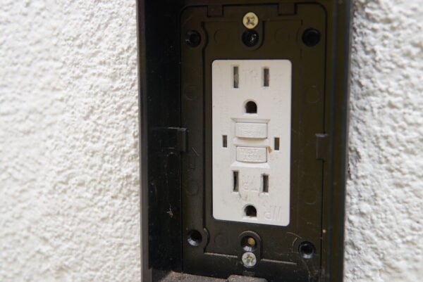 Close-up of a GFCI electrical outlet installed on a white wall, designed for safe and reliable use in basements and attics.