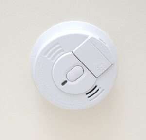White ceiling-mounted smoke detector with a circular design and vented casing for detecting smoke and fire hazards.