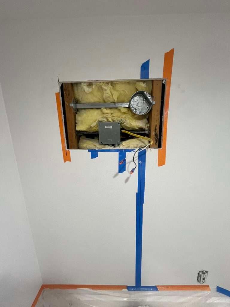 Exposed drywall cutout with visible electrical wires and insulation during outlet installation by LA Pro Electrical in Los Angeles, CA.